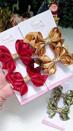 three red, gold and green hair bows on top of each other next to christmas tree