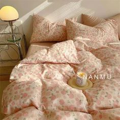 an unmade bed with pink and white flowers on it