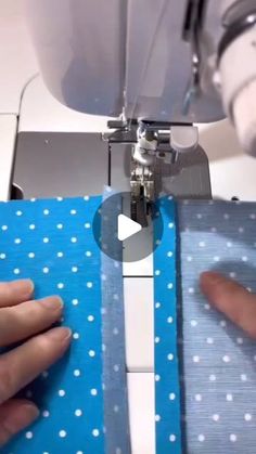 someone is using a sewing machine to sew something on a piece of blue fabric