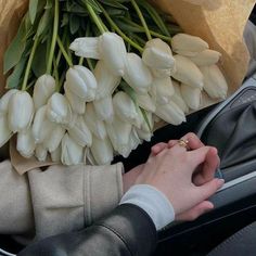 a bouquet of white tulips is being held by a woman in a car