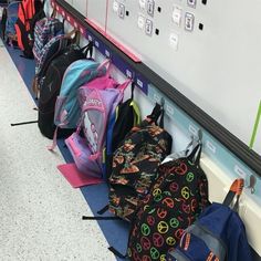 several backpacks lined up against the wall in a school hallway, all with peace signs on them