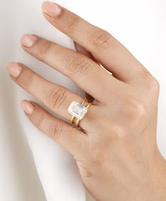 a woman's hand with a ring on her finger and a white napkin in the background