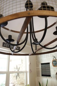 a chandelier hanging from the ceiling in a living room with a window behind it