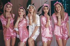 four women in pink pajamas posing for the camera with their hands on their chins