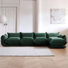 a green couch sitting on top of a wooden floor next to a white rug in a living room