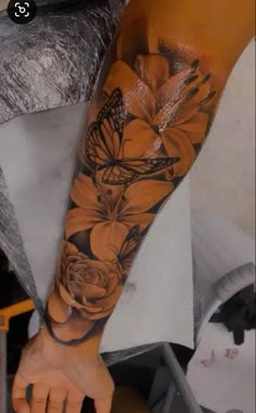 a woman's arm with a butterfly and flower tattoo on the left side of her arm