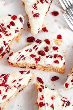 several pieces of cake with white frosting and cranberry toppings next to a fork