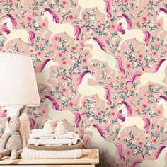 a pink wallpaper with unicorns and flowers on it, next to a lamp