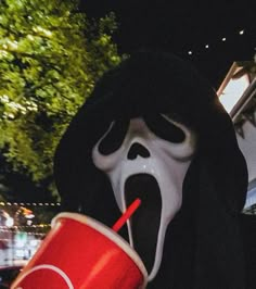 a person wearing a mask and holding a drink in their hand with the mouth open