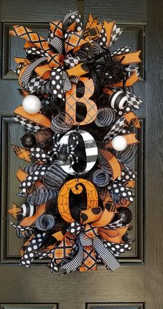 an orange and black wreath with the letter b on it is hanging on a door