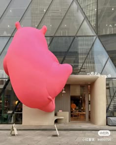 a giant pink bear statue sitting in front of a building