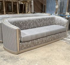 a grey couch sitting on top of a floor next to a pile of wood planks