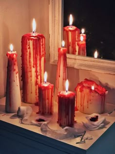 five candles with blood running down them on a table next to a window sill