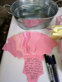 pink paper cutouts are sitting on a table next to some markers and pencils