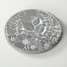 a round metal object with flowers and leaves on it