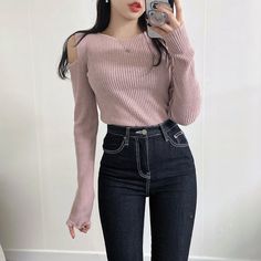 a woman taking a selfie with her cell phone wearing jeans and a pink sweater