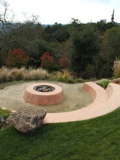 an outdoor fire pit surrounded by grass and rocks