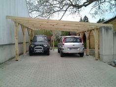 two cars are parked under a wooden structure