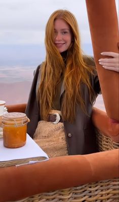 a woman standing next to a hot dog on top of a table