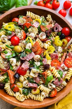 a bowl filled with pasta salad next to tomatoes