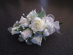 a bridal bouquet with white flowers and greenery on a black countertop,