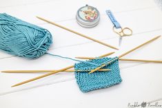 yarn, knitting needles and scissors on a white table