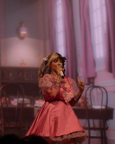 a woman in a pink dress singing into a microphone