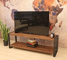 a flat screen tv sitting on top of a wooden stand next to a potted plant