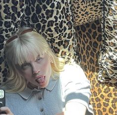 a woman taking a selfie with her cell phone in front of leopard print pillows