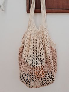 a crocheted bag hanging from a hook on a wall next to a coat rack