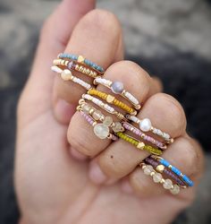 a person is holding several rings in their hand and wearing them with different colors on them