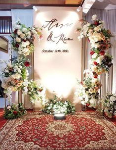 a floral wedding arch with flowers and greenery on the floor in front of a white wall