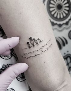 a small tattoo on the arm of a woman with three birds sitting on top of it