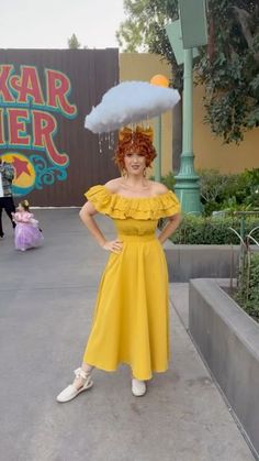 a woman in a yellow dress is holding an umbrella over her head and posing for the camera