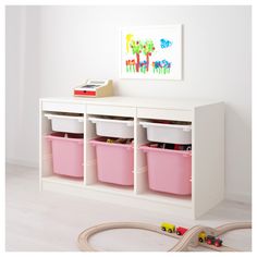 a toy train set sitting on top of a white shelf next to pink bins