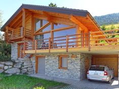 a car is parked in front of a house with wooden railings and balconies