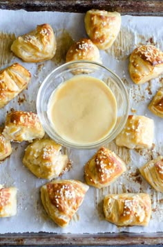 a tray filled with pastries next to a bowl of dipping sauce