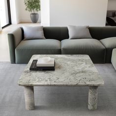 a marble coffee table sitting on top of a gray rug in front of a couch