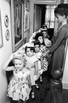 black and white photograph of children with hats on their heads in an old house hallway