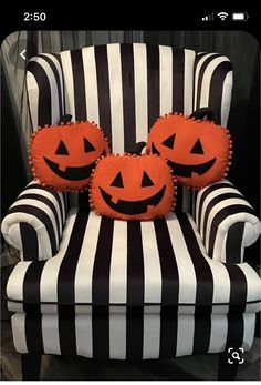 two pumpkin pillows sitting on top of a striped chair