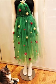 a cat sitting next to a mannequin wearing a green dress