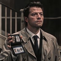 a man in a trench coat holding an award