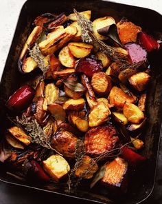 roasted potatoes and carrots in a baking pan with herbs on the side, ready to be cooked