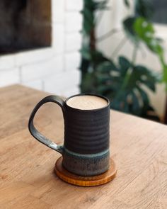 a black mug sitting on top of a wooden table