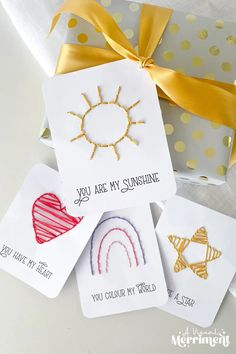 four handmade cards with different designs and sayings in front of a gift box