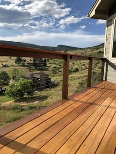 a wooden deck with a house in the distance and clouds overhead on a sunny day