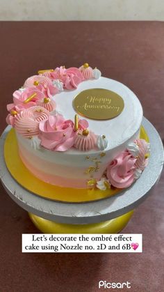 a birthday cake with pink flowers on top and gold lettering that reads happy birthday let's decorate the ombre effect