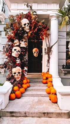 a house decorated for halloween with pumpkins and skulls on the front porch, along with decorations