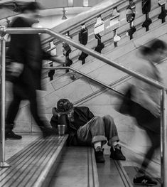 black and white photograph of people on escalator with man sitting in the middle