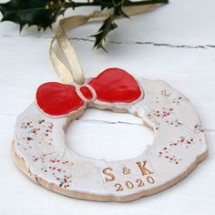 a christmas wreath ornament with a red bow on it sitting next to greenery